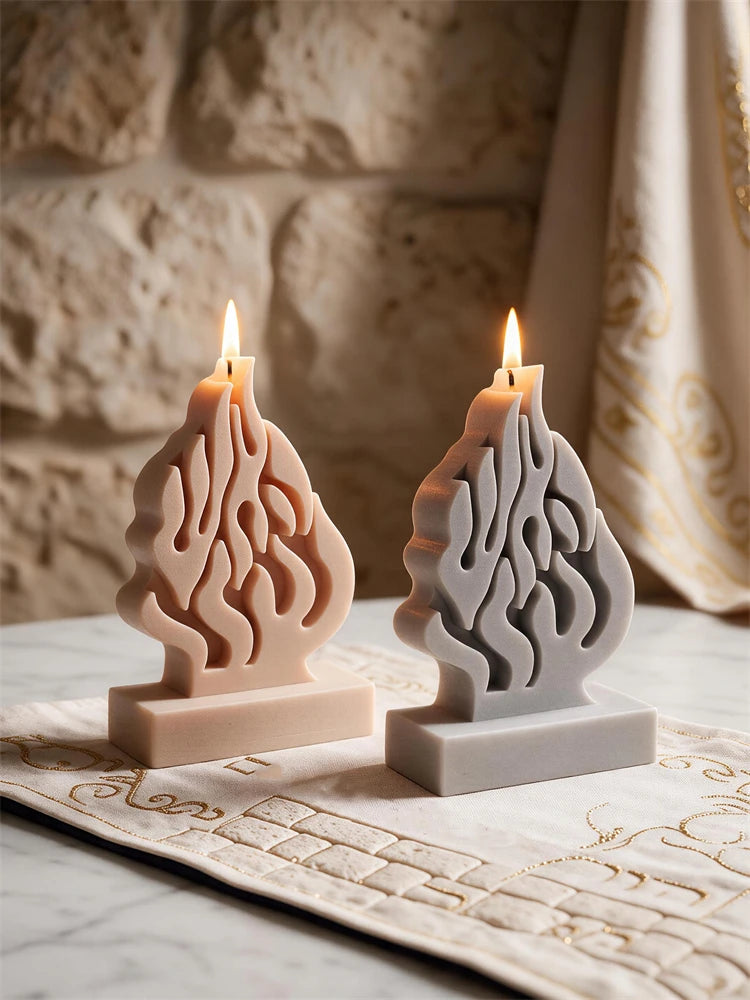Two flame-silhouette candles on rectangular bases with their wicks lit