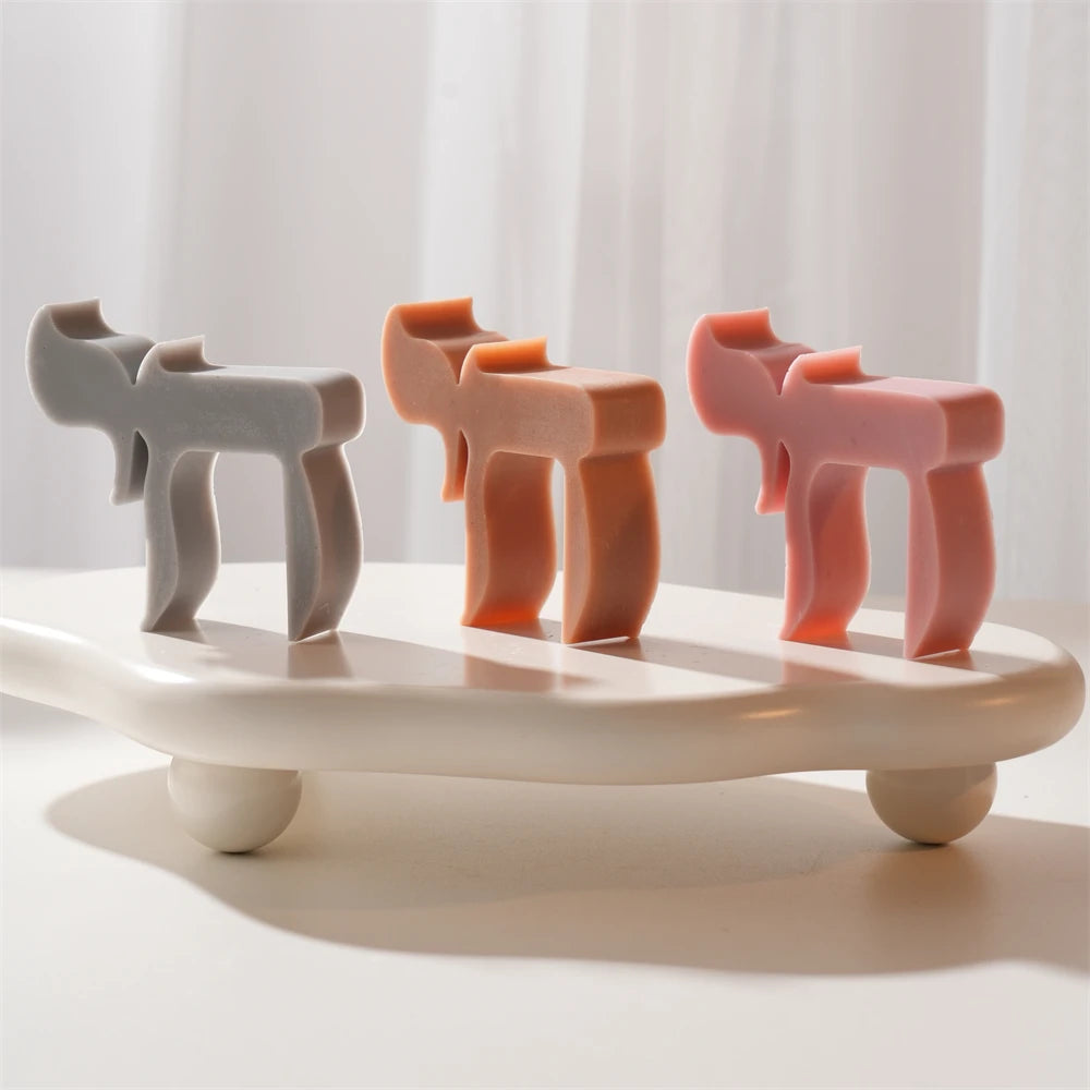 Three sculptural Hebrew Chai candles on a white display tray