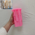 Pink silicone EID tower mold held beside example castings