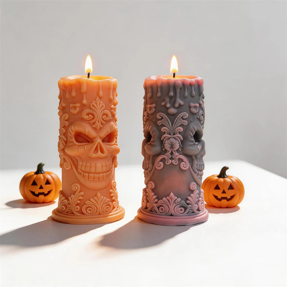 Two ornate skull pillar candles with floral scrollwork