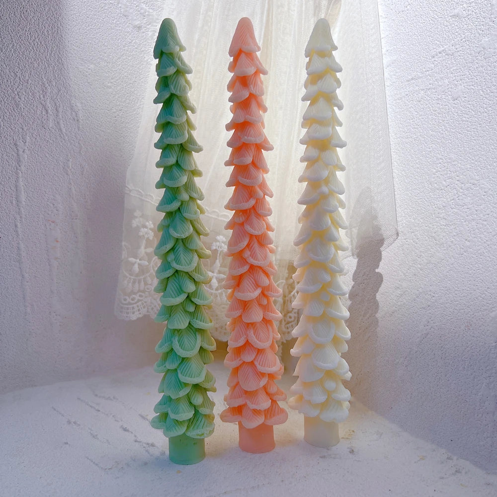 Three slender layered tree candles standing upright