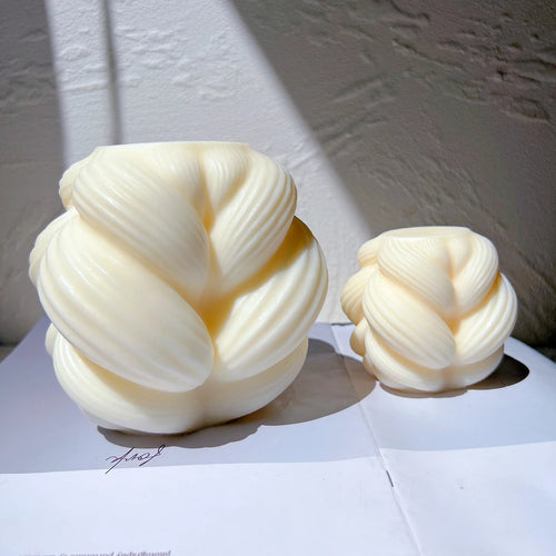 Two knot-inspired candle forms in different sizes
