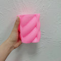 Pink rounded rope-twist silicone mold held in one hand