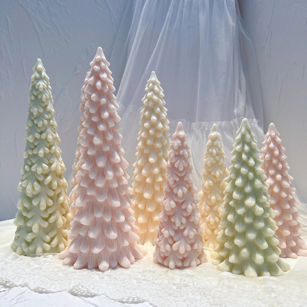 Multiple tall and medium snow-covered tree candles arranged on a white surface