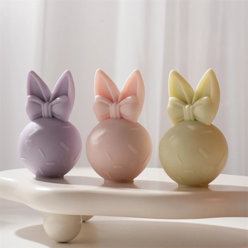 Three bow-topped egg bunnies on a display stand