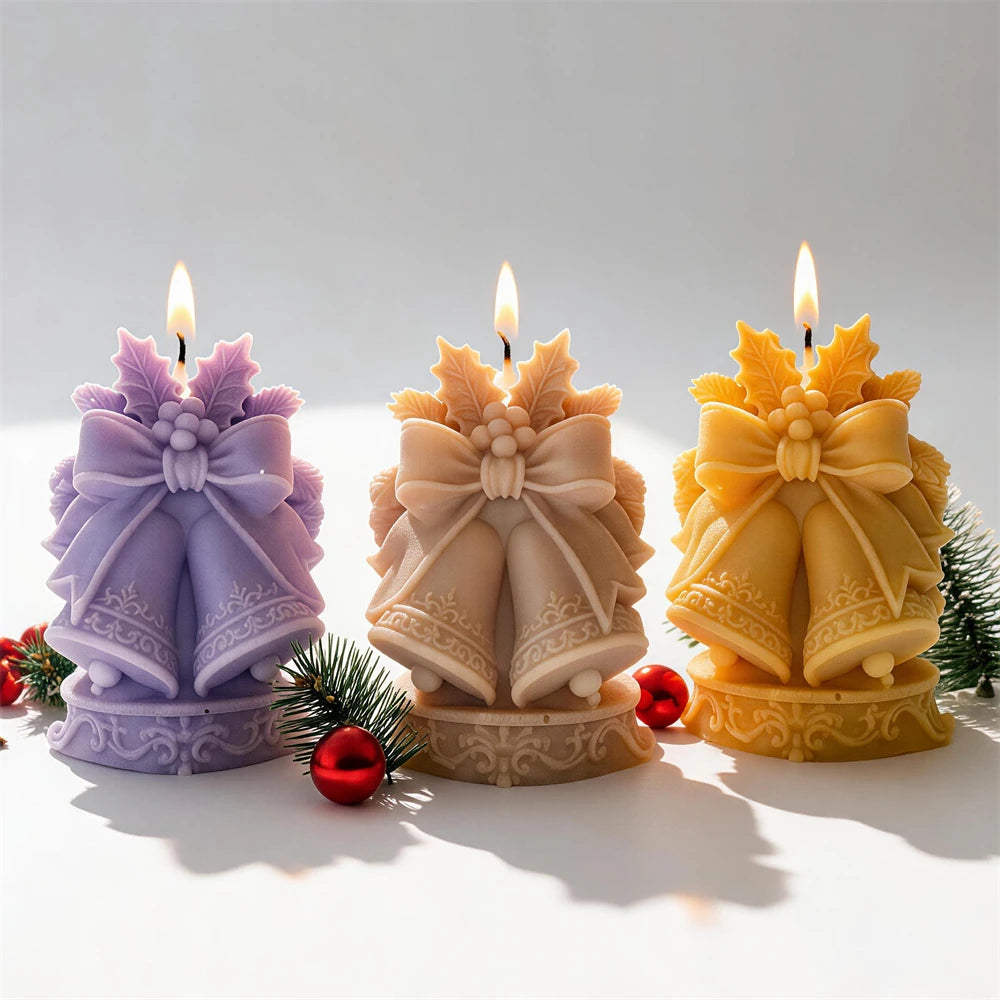 Three Christmas bell candles on ornamental bases