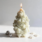 Cream pinecone candle showing its raised bell, bow and berry motifs