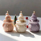 Group of snowman candles showing smiling faces and knitted coats