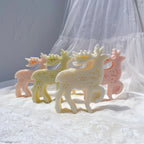 Several snowflake-textured reindeer candles arranged on a white cloth