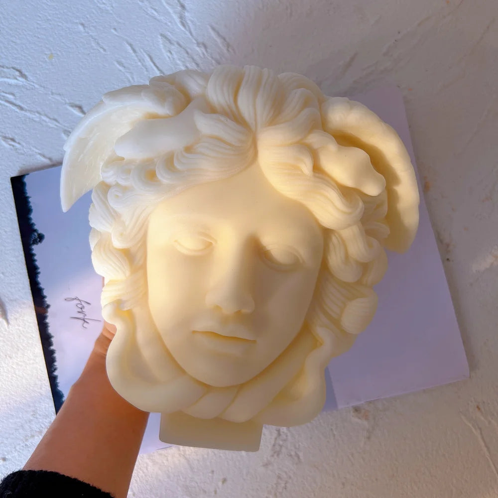 Medusa face casting held to show raised facial relief