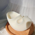 Angled view of sculptural white vessel with two different-sized open recesses