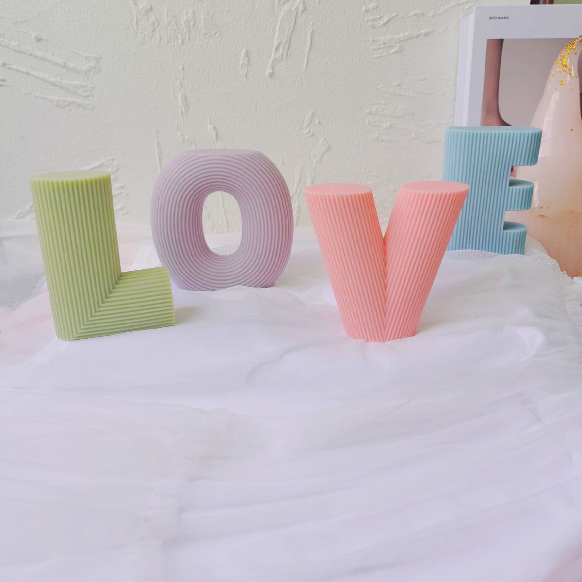 Ribbed L, O, V and E letter candle samples arranged to spell LOVE