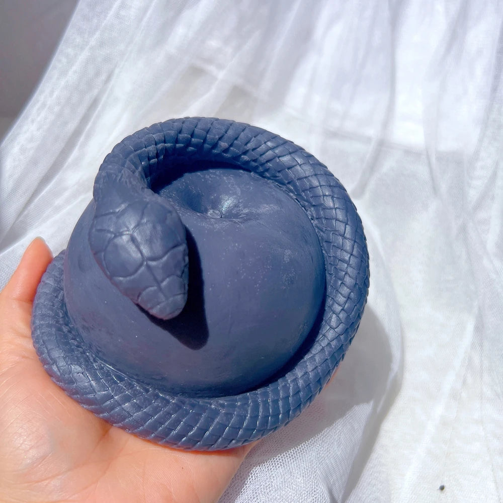 Dark blue snake-and-apple casting held in one hand